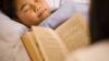 : A boy lies in bed, listening to his parent read a bedtime storybook, in English 