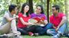 Group of students sitting on the ground viewing an IELTS brochure